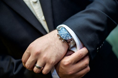 Groom getting ready on his wedding day wearing a black suit, Hugo Boss watch and ring