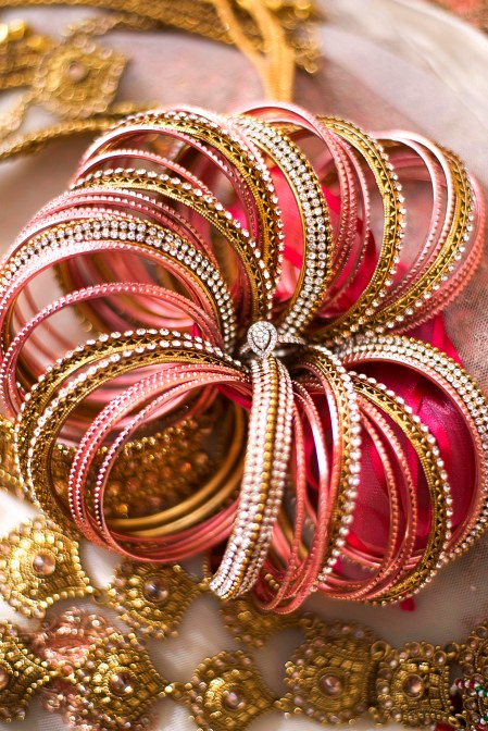 Silver wedding ring in the middle of gold, pink and silver bangles
